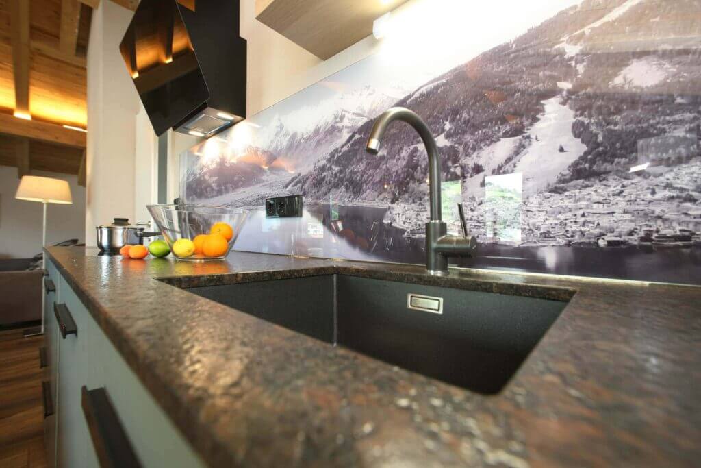 Moderne Küche mit Granitplatte, Obst und Bergblick im Hintergrund. Ideal für Familienurlaub.