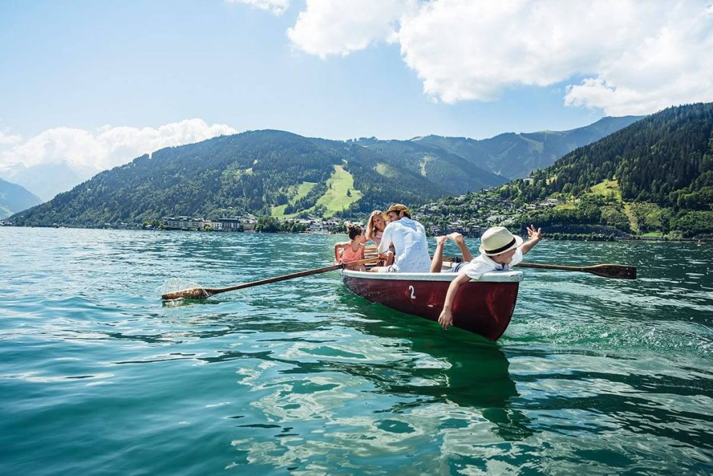 Familie rudert im Boot auf dem Zeller See, Umgebung mit Bergen und Natur.