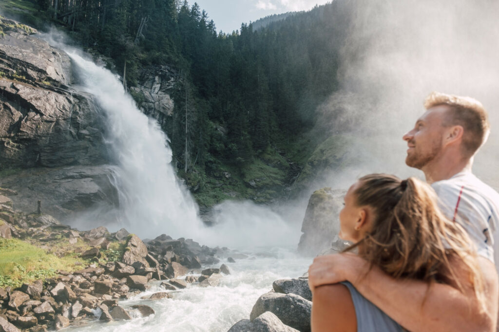 Couple looks at a large waterfall in the mountains